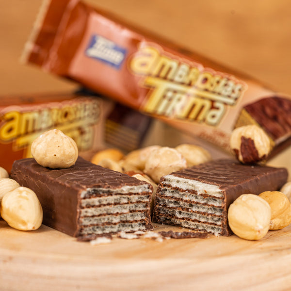 Crispy milk chocolate wafers with hazelnut cream by Tirma split in half and surrounded by hazelnuts and packed wafers.