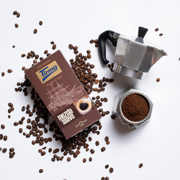 Tirma Soft Ground Blend Coffee placed next to scattered coffee beans and a mug of ground coffee. Spanish Coffee made in Spain.