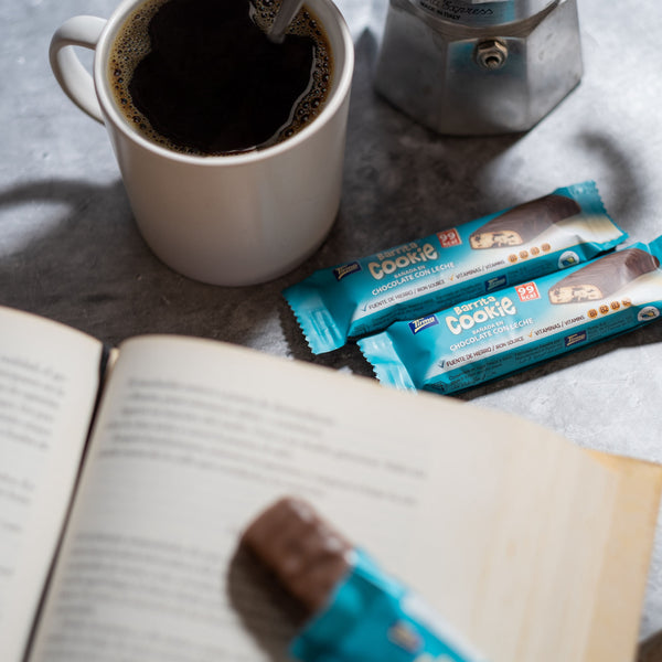 Tirma Chocolate Chips Biscuit Bars Covered with Milk Chocolate placed next to a cup of coffe and a book. Spanish chocolate chips biscuit bar made in Spain.