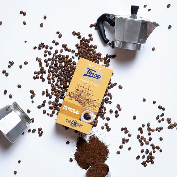 Tirma Torrefacto coffee, 250g placed next to coffee beans and a ground coffee. Spanish Coffee made in Spain.