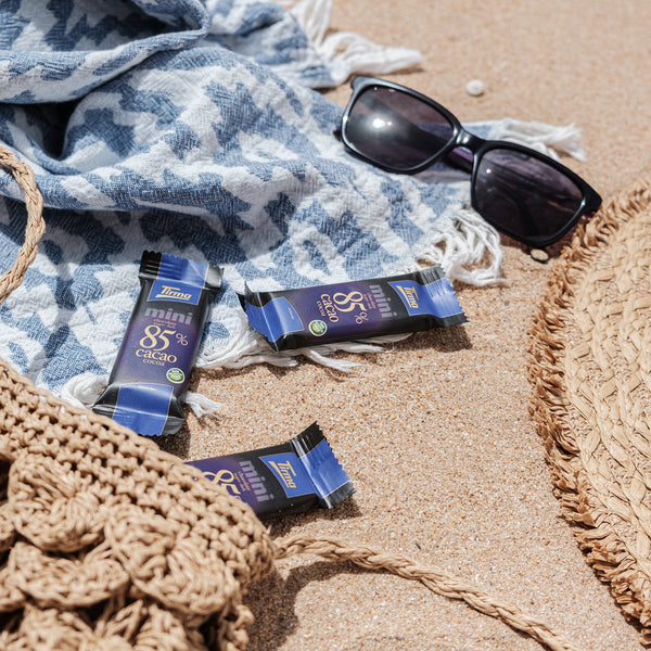 Tirma Mini 85% Dark Chocolate Bars 180 g. 3 mini chocolate on the sand with sunglass. Spanish mini dark chocolate made in Spain.