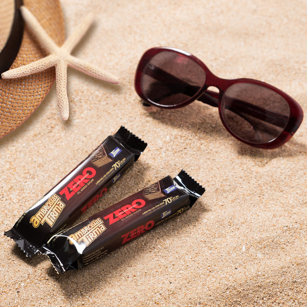 Two individual 70% dark chocolate wafers on sand. Placed next to a starfish, a sombrero and sunglasses on sand. Tirma's Chocolate Wafers Photography. Spanish dark chocolate wafers in the UK