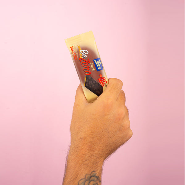 Tirma Snack Be Zero 70% dark chocolate biscuit bar being held by a hand with a tattoo on his arm. Spanish biscuits made in Spain.