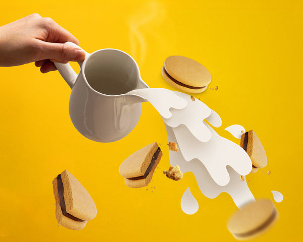 White mug being tilted over cookies with a yellow background