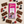 A milk chocolate bar package labeled Tirma, surrounded by assorted berries and chocolate pieces on a light beige surface. The package is pink and purple with fruit illustrations, and the surrounding food includes raspberries, blueberries, blackberries, and chocolate bars.