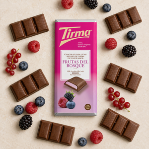 A milk chocolate bar package labeled Tirma, surrounded by assorted berries and chocolate pieces on a light beige surface. The package is pink and purple with fruit illustrations, and the surrounding food includes raspberries, blueberries, blackberries, and chocolate bars.