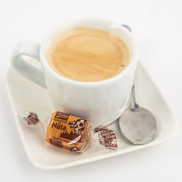 Tirma Cream Caramel Candy placed next to a cup of caramel coffee and a spoon. Spanish cream caramel candy made in Spain.