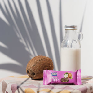 Coconut Biscuit covered in Milk Chocolate 200 g - placed next to the bottle of milk and a coconut. Spanish coconut biscuits made in Spain.