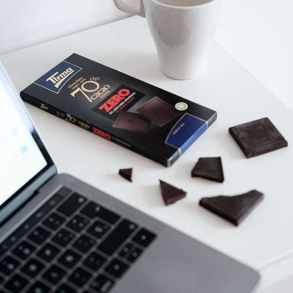 Tirma ZERO Dark Chocolate Bar 70% cocoa no added sugars and gluten free placed beside with the laptop and a white mug. Spanish chocolate bar made in Spain.
