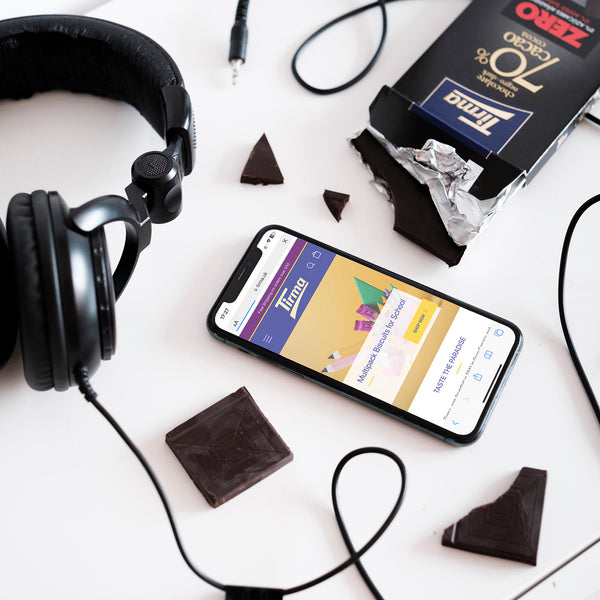 Tirma ZERO Dark Chocolate Bar 70% cocoa no added sugars and gluten free cuts placed next to headphone and an android phone. Spanish chocolate bar made in Spain.