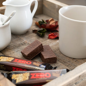 3 of Tirma's 70% Dark Chocolate Wafers, placed on a breakfast tray with dry flowers, white mug, white milk jug and white sugar pot. One dark chocolate wafers is open and split in two. Tirma's Chocolate Wafers Photography. Spanish wafers in the UK